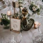 centre de table invités avec vieux objets, bougeoirs dorés et fioles fleuries pour un mariage élégance végétale