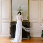 Mariée devant la cheminée avec une enfant qui tient la traine de la robe