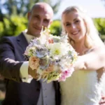 Mariés radieux montrant le bouquet de la mariée, Organisation de mariage dans le nord, couple de mariés avec un bouquet de fleurs